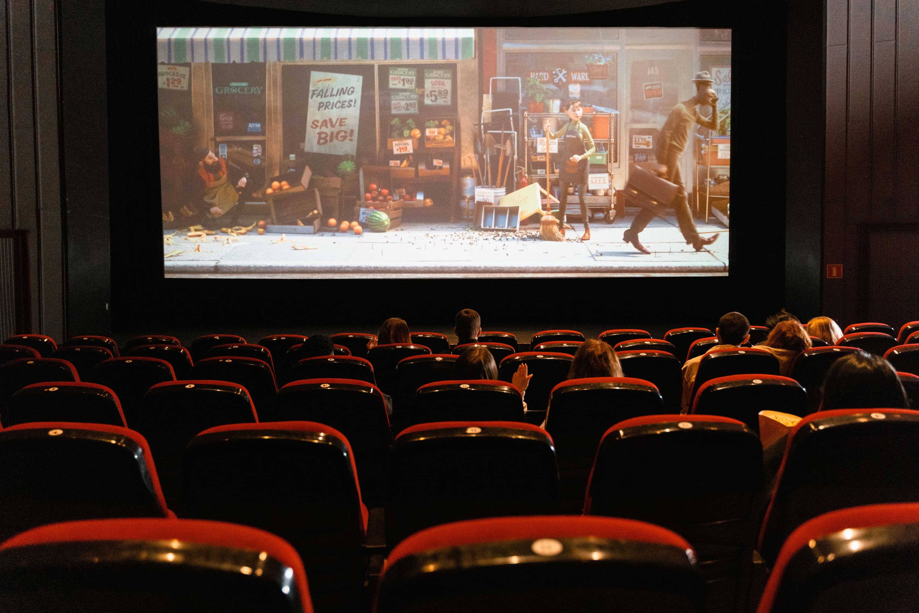 Salle de cinéma vue de dos, spectateurs face à un grand écran